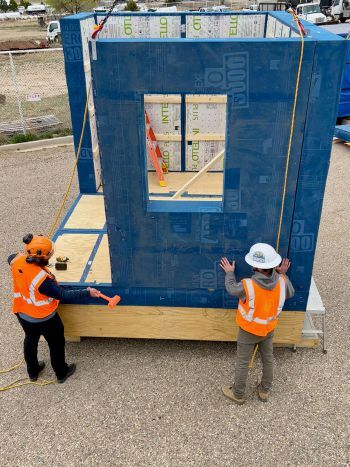 Students adjust a wall panel to make sure it’s lined up before fastening the tie
downs. Courtesy B.Public Prefab