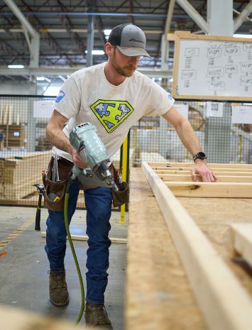 Bensonwood apprentice Drew DiSilva prefabricates wall components at
Bensonwood’s Keene, N.H. facility. Photo by Zach Davidson for Bensonwood