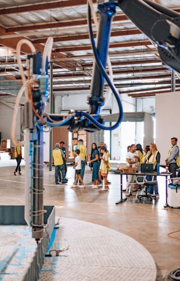 Visitors watch the 3D printing process at the Azure Printed Homes manufacturing facility. Photo: Azure Printed Homes.