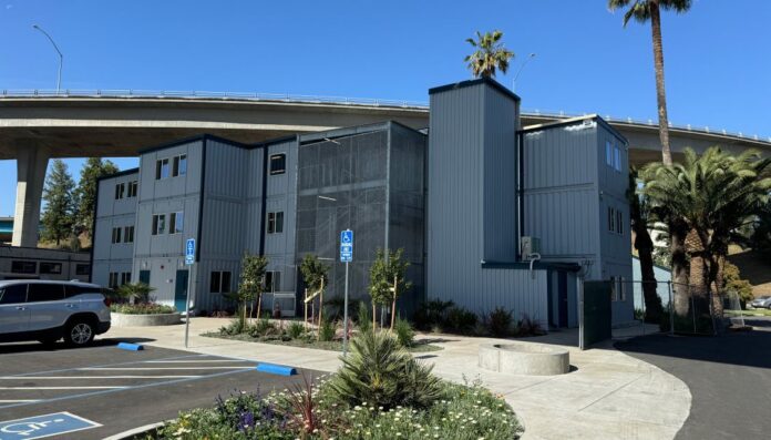 Tucked between two highway overpasses in Stockton, California this site had only 13,000 sq. ft. of buildable space and the grant required at least 150 beds. RPM Team designed and managed construction of a three-story, 11,000 sq. ft. container-based navigation center providing homes for the formerly homeless. Credit: RPM Team