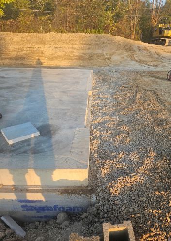 On the right-hand edge of the slab, you can see the cut-out for the door buck that Bensonwood specifies. However, contrary to the company’s specifications, the vapor barrier here hasn’t been left hanging out from under the slab. Credit: Bensonwood