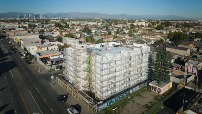 The building consists of 70 modules, each on a 420 sq. ft. standardized chassis. Ground broke in June 2025, and the building was set in 10 working days. After stacking, SoLa takes care of unit-to-unit utility connections, dry-in, roofing, exterior cladding, finishes and landscaping. Residents are expected to start moving in during May or June 2026.